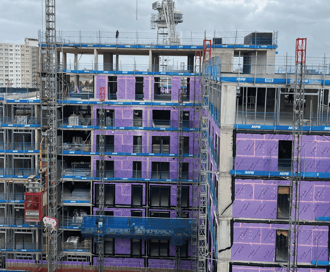 Anchor Works close-up: mid-rise floors under construction with insulation panels and scaffold encasement