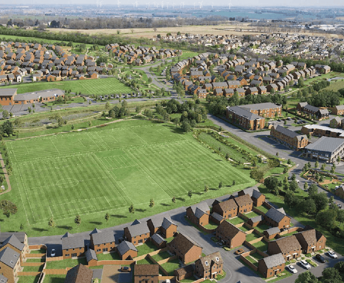 Glenvale Park aerial view: completed estate with sports field, surrounding development and distant wind turbines