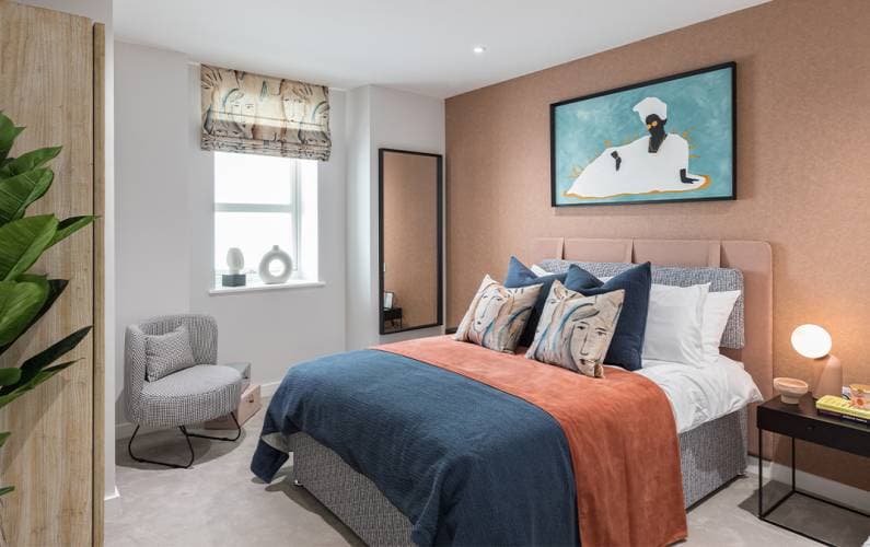 Wyndham Studios show flat interior: double bedroom with feature artwork, fabric headboard and styled bed linen